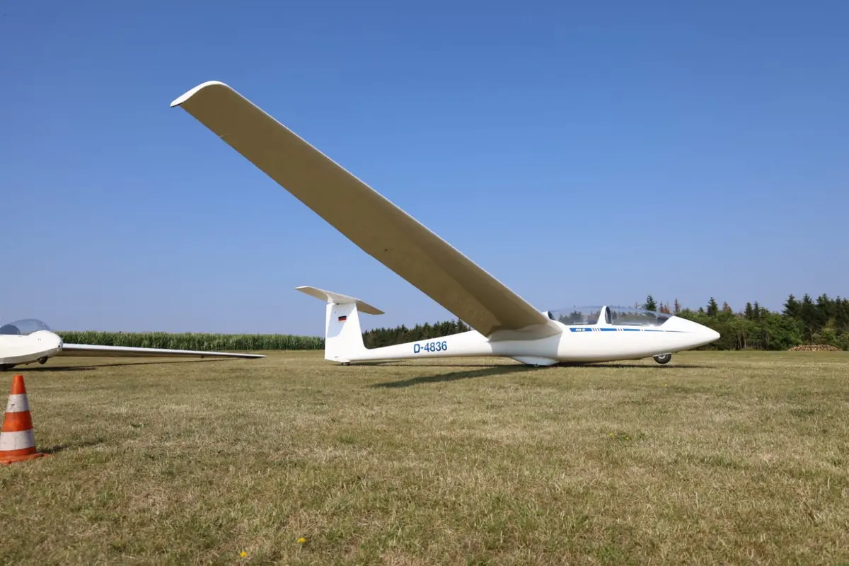 Segelflugzeug ASK 21 D-4836 auf dem Gras, die lange Tragfläche ragt in den Himmel