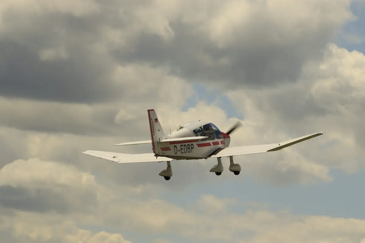 Robin im Landeanflug unter Quellwolken