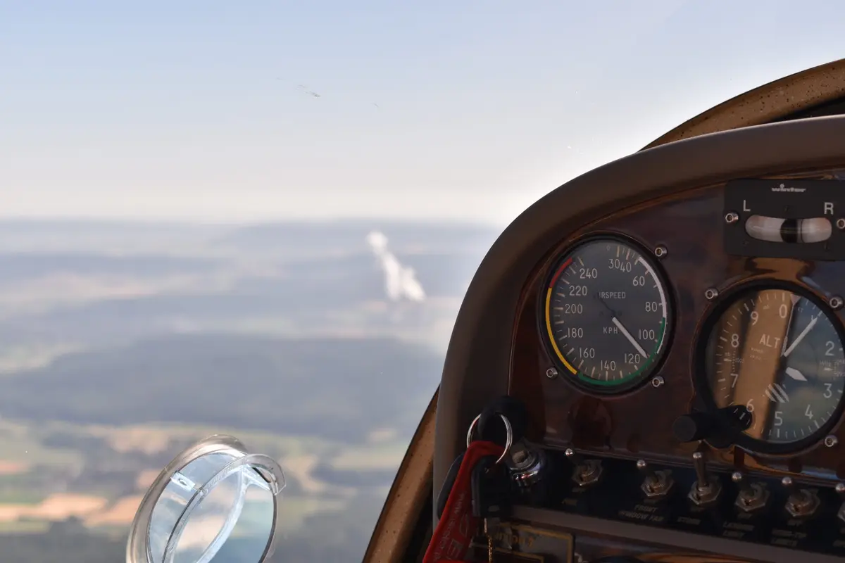 Fluginstrumente im Cockpit, im Hintergrund die Landschaft im Dunst