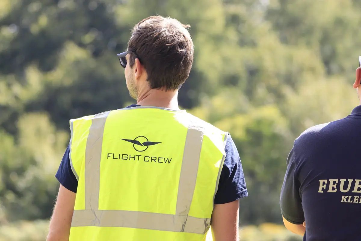 Helfer in Warnweste „Flight Crew“ beobachtet das Flugprogramm