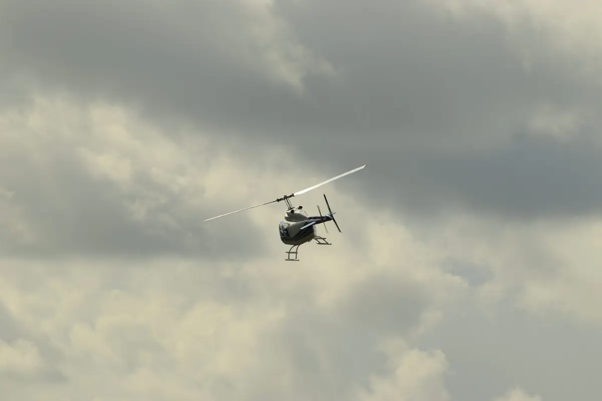 Hubschrauber im Rundflug vor grauem Himmel