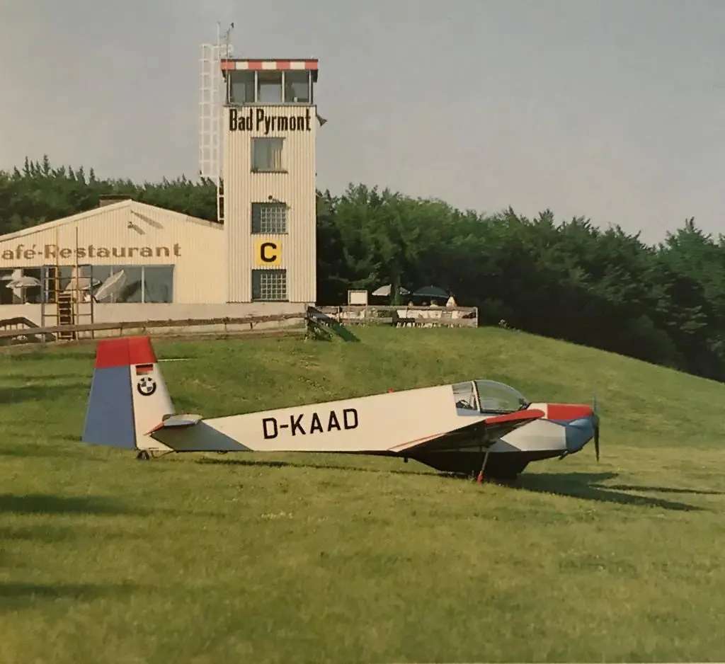 Historisches Foto: Tower und Café-Restaurant des Flugplatzes Bad Pyrmont, davor die D-KAAD auf der Wiese